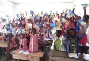 Students in Madagascar hold the Ako books in the air