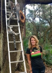 Elizabeth Moore standing in front of a tree with ring-tailed lemurs